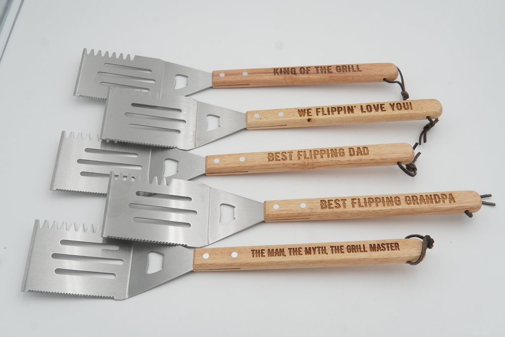 Set of five engraved spatulas with wooden handles on a white background
